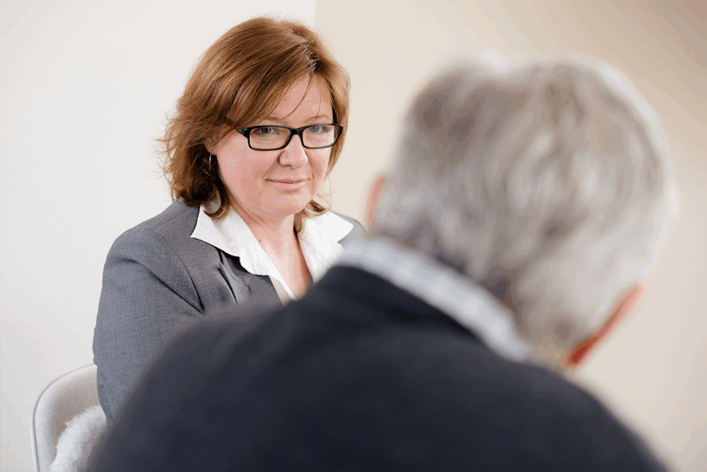 Katja Lauen im Anzug und mit Brille schaut einen Mann an