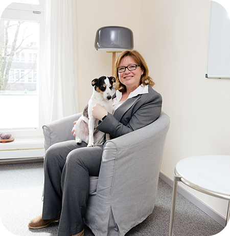 Katja Lauen sitzt auf einem Stuhl und hält einen Hund im Arm.