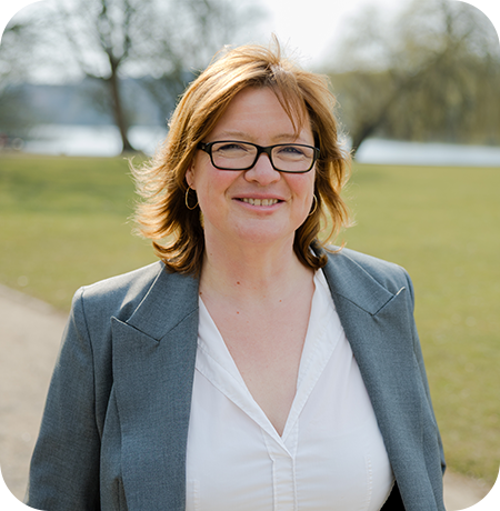 Katja Lauen draußen im Anzug und mit Brille.
